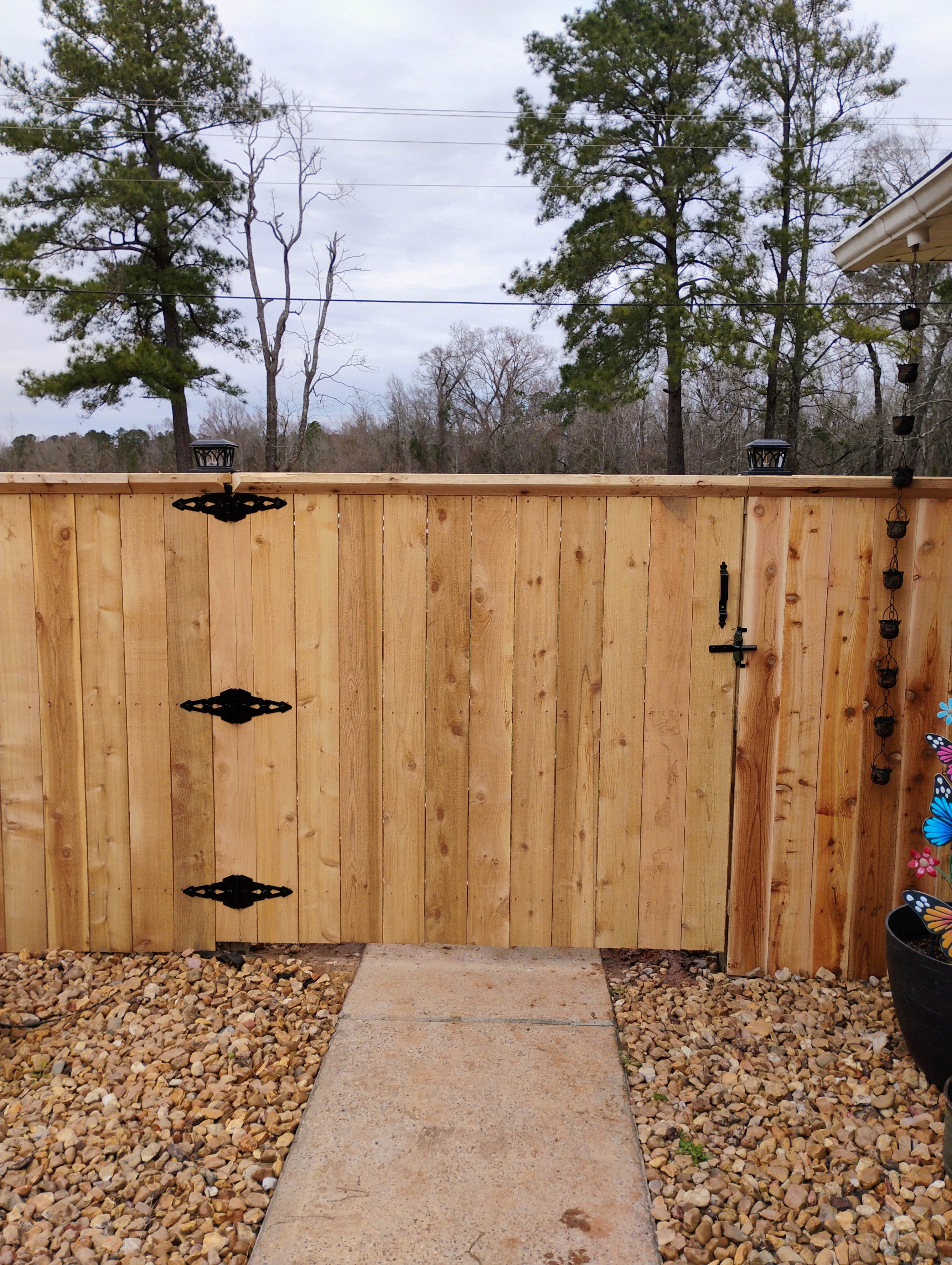 Cedar privacy fence with decorative black iron gate hardware and solar post caps – Fortified Fence and Weld