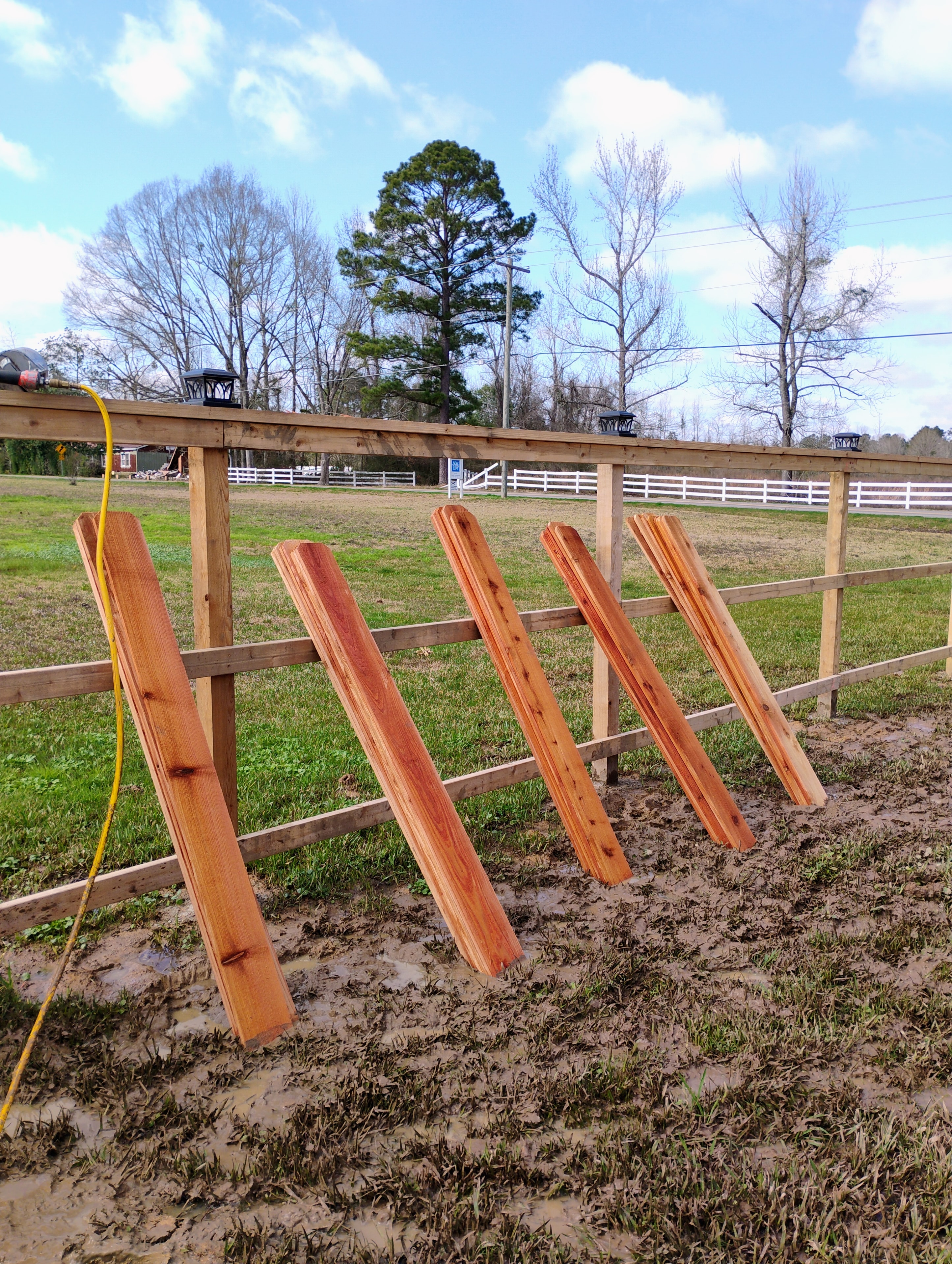 Cedar fence installation in progress — pickets staged on frame in rural Louisiana – Fortified Fence and Weld