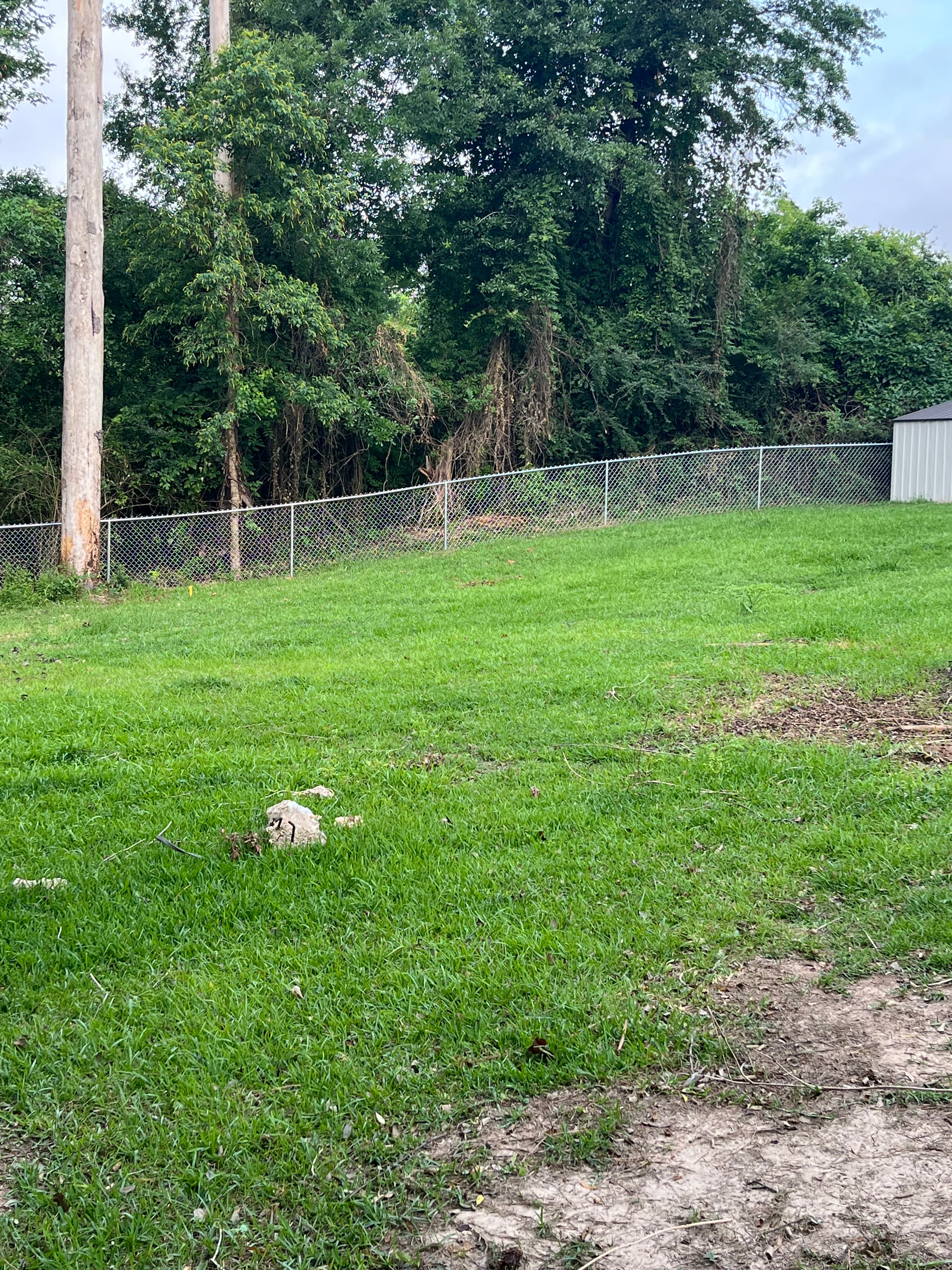 Chain link fence along rural treeline and metal building in Central Louisiana – Fortified Fence and Weld