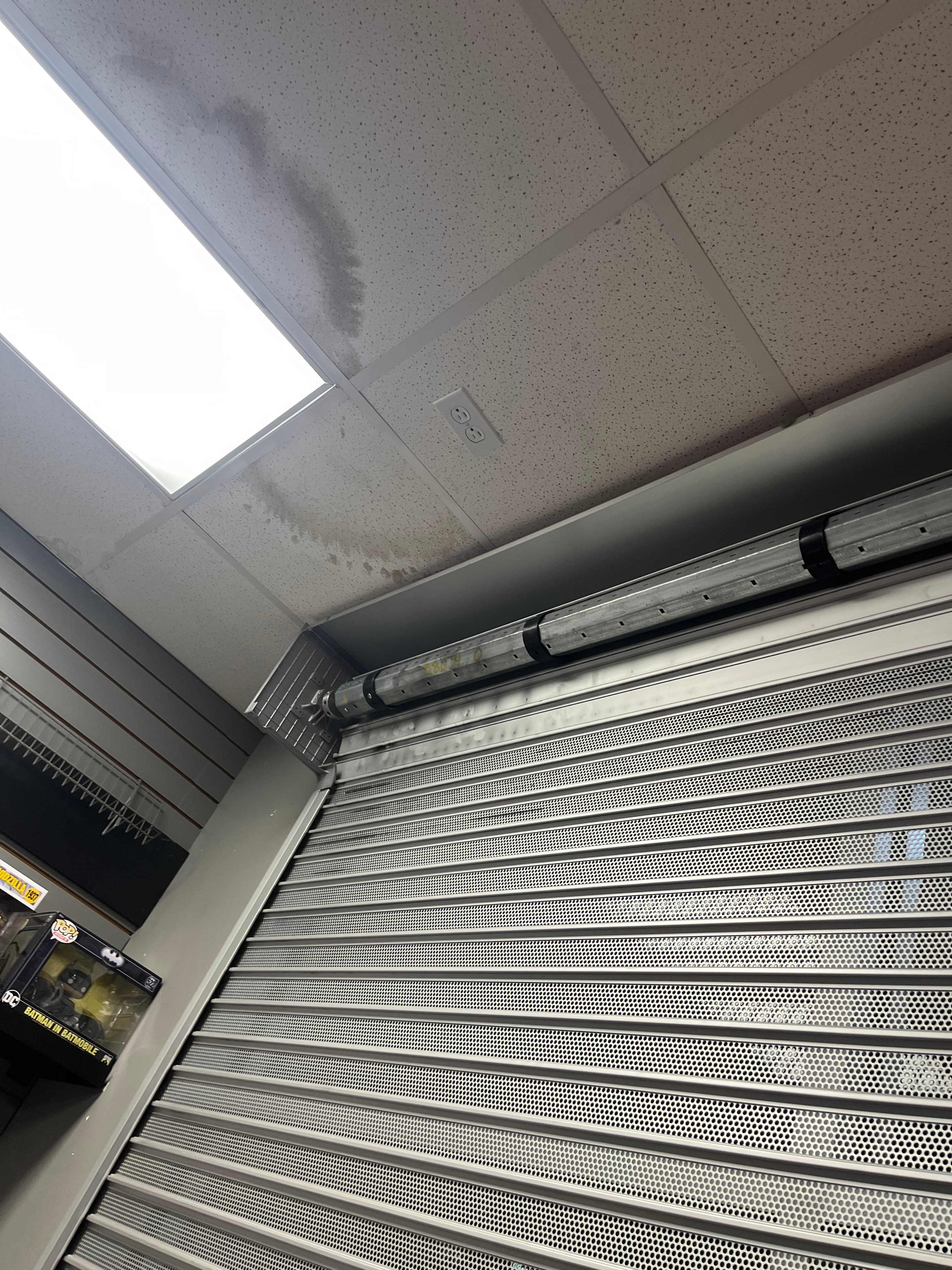 Perforated metal security grille rolling door installed at commercial storefront — Fortified Fence and Weld, Alexandria LA