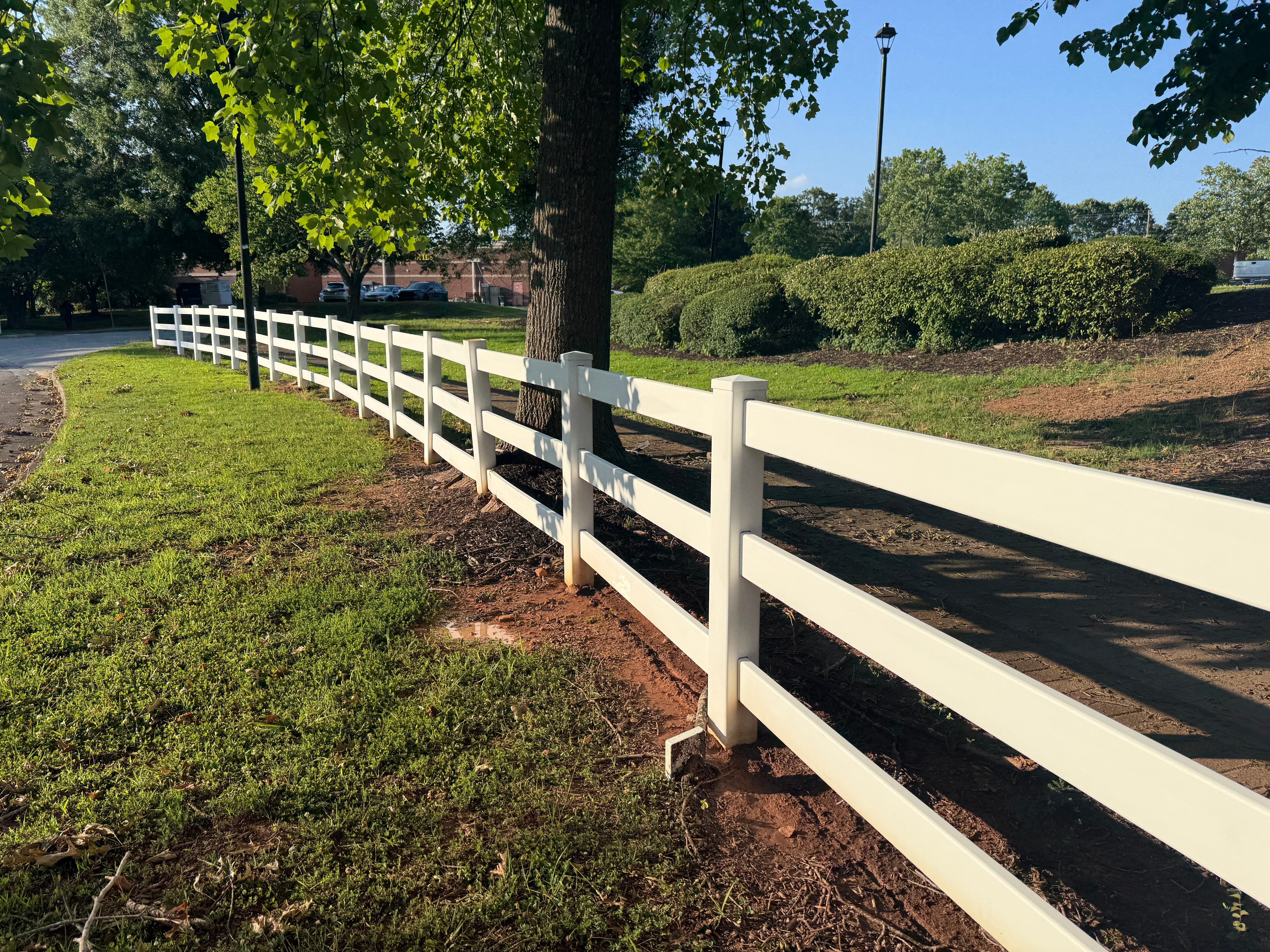 White vinyl 3-rail fence in pastoral green setting with mature trees — Fortified Fence and Weld, Central Louisiana