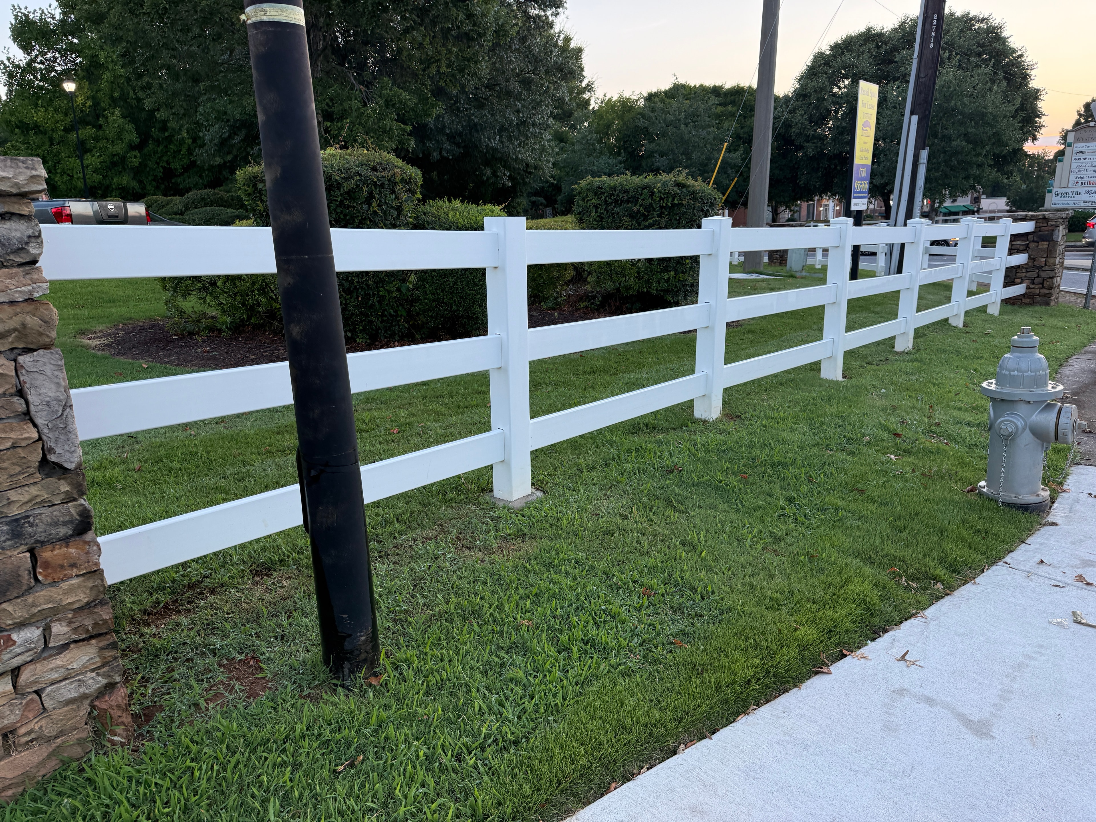 White vinyl 3-rail fence at corner near stone wall and lamp post — Fortified Fence and Weld, Central Louisiana