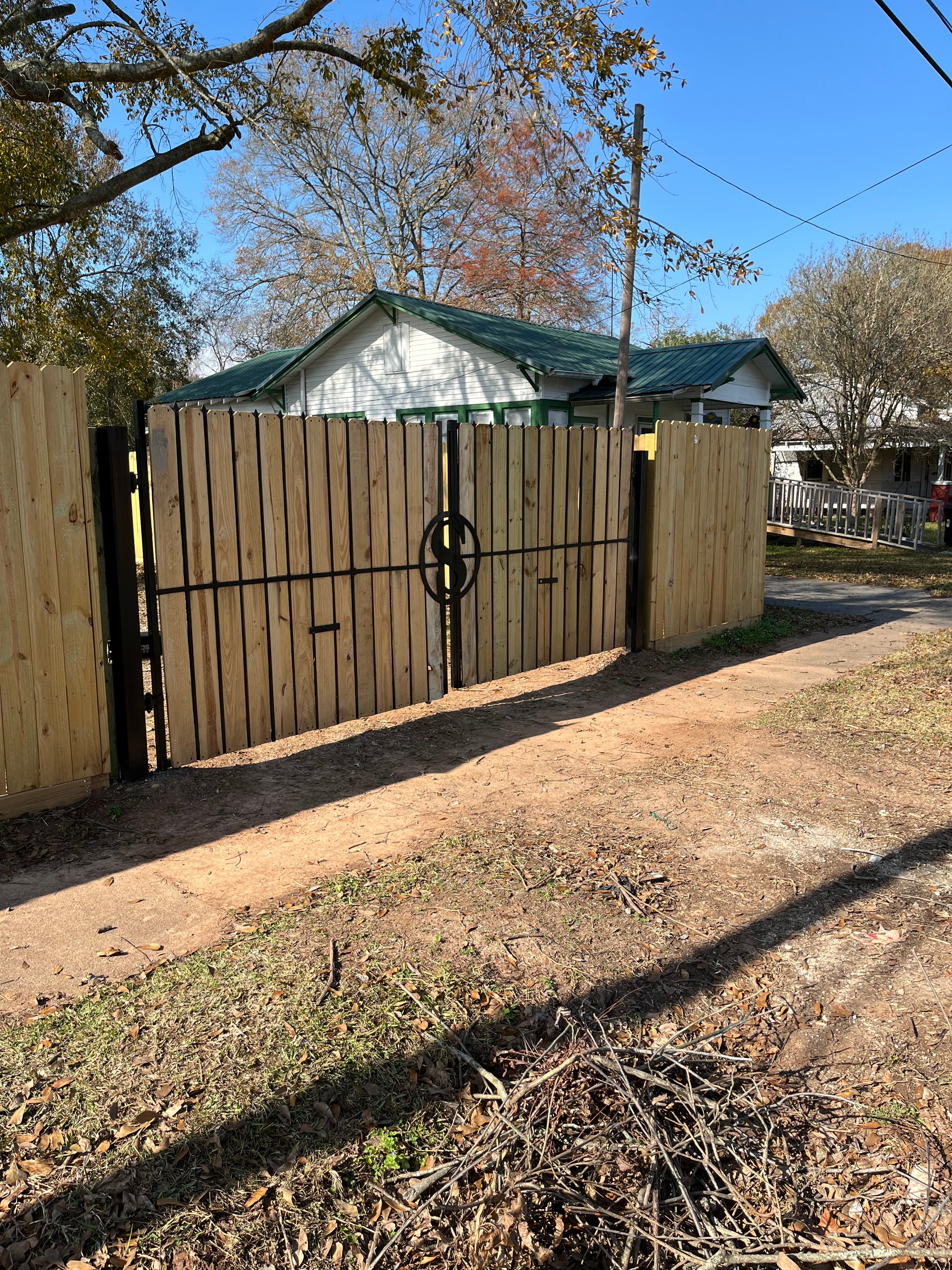Custom wood horizontal slat double swing gate with decorative iron circle medallion installed at rural property — Fortified Fence and Weld, Alexandria LA
