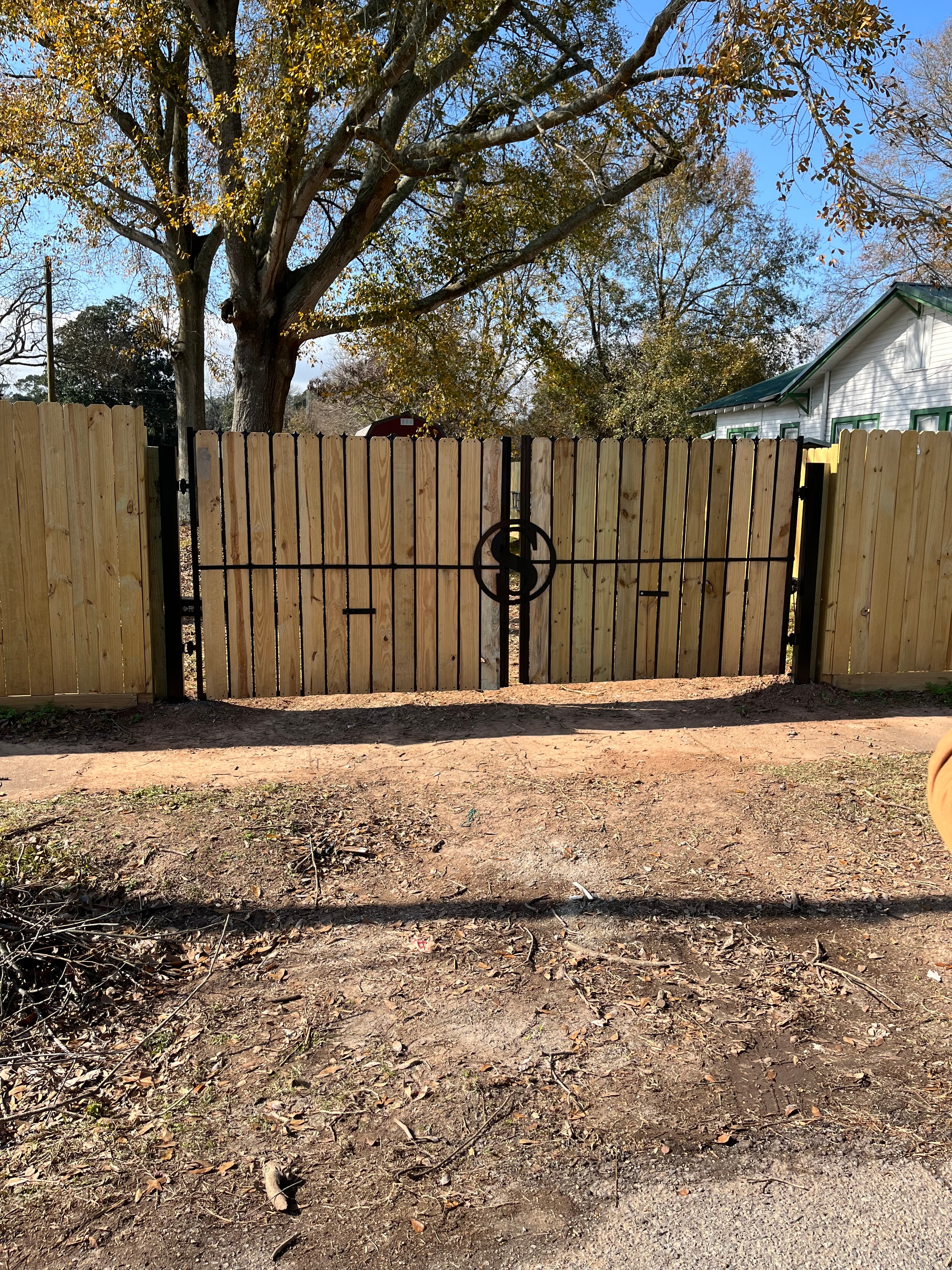 Custom wood horizontal slat double swing gate with decorative iron medallion, front view — Fortified Fence and Weld, Central Louisiana